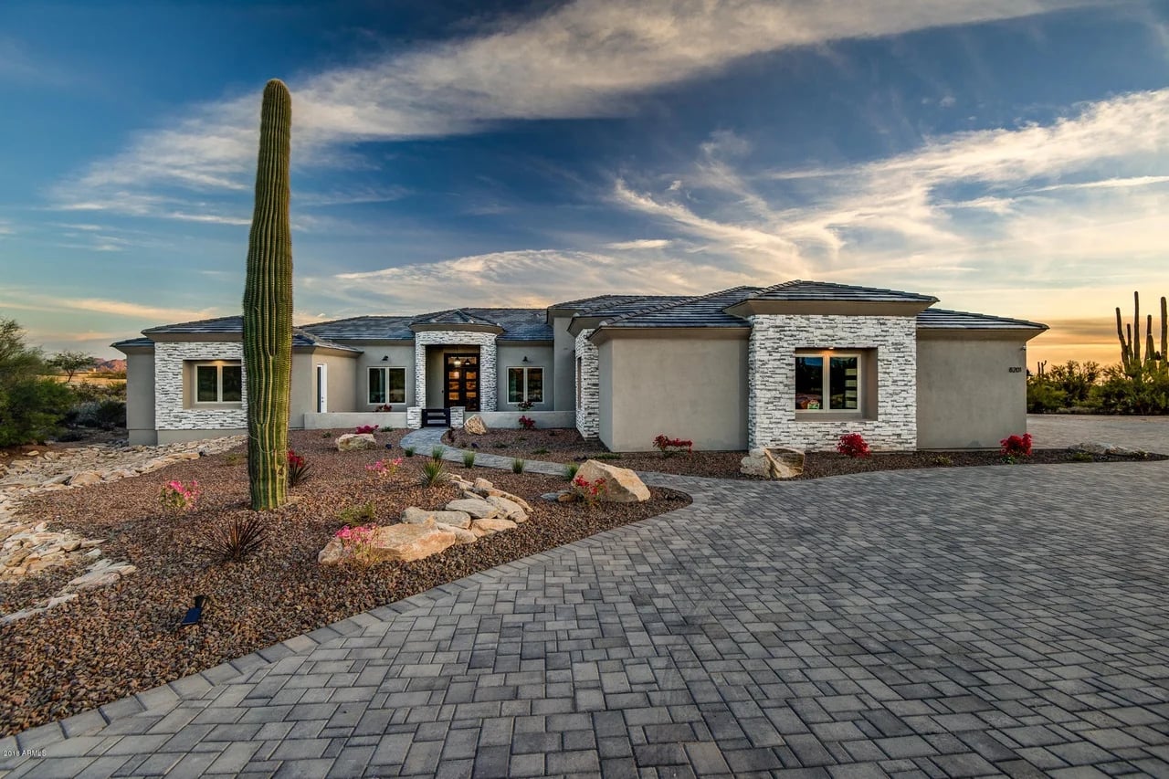 A saguaro frames the Smokehouse Trail residence beneath an evening sky.